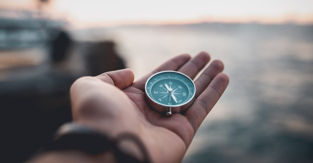 hand with compass looking out to sea