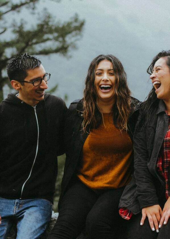 Three friends laughing outdoors happily